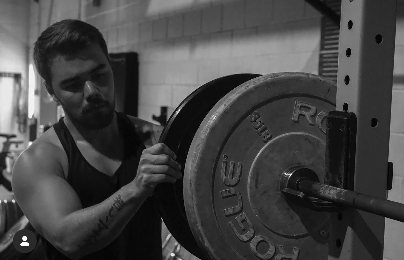 Cameron Sato loading a plate onto a barbell
